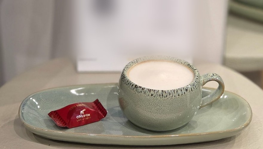 Cappuccino in een groen kopje met een chocolaatje op het schoteltje